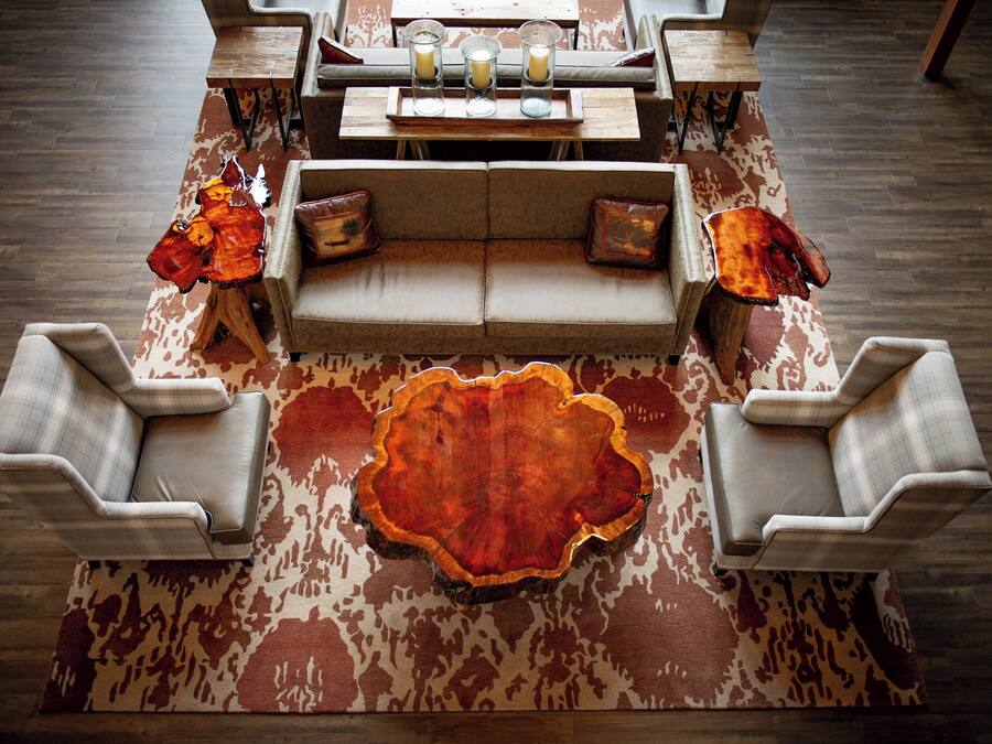 Uma sala de estar moderna com um sofá central, duas poltronas, uma mesa de centro e um tapete decorativo.