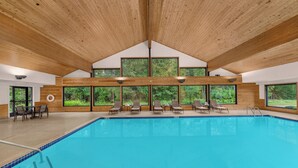 A large indoor swimming pool with wooden beams, multiple windows, and lounge chairs. - Holiday Inn Express & Suites Hayward by IHG (Hayward)
