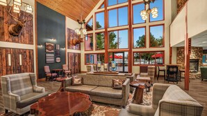 A spacious lobby with large windows, wooden walls, and a variety of seating options including sofas and armchairs. - Holiday Inn Express & Suites Hayward by IHG (Hayward)