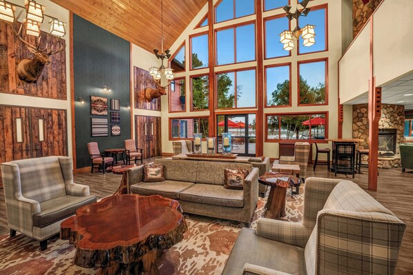 A spacious lobby with large windows, wooden walls, and a variety of seating options including sofas and armchairs.