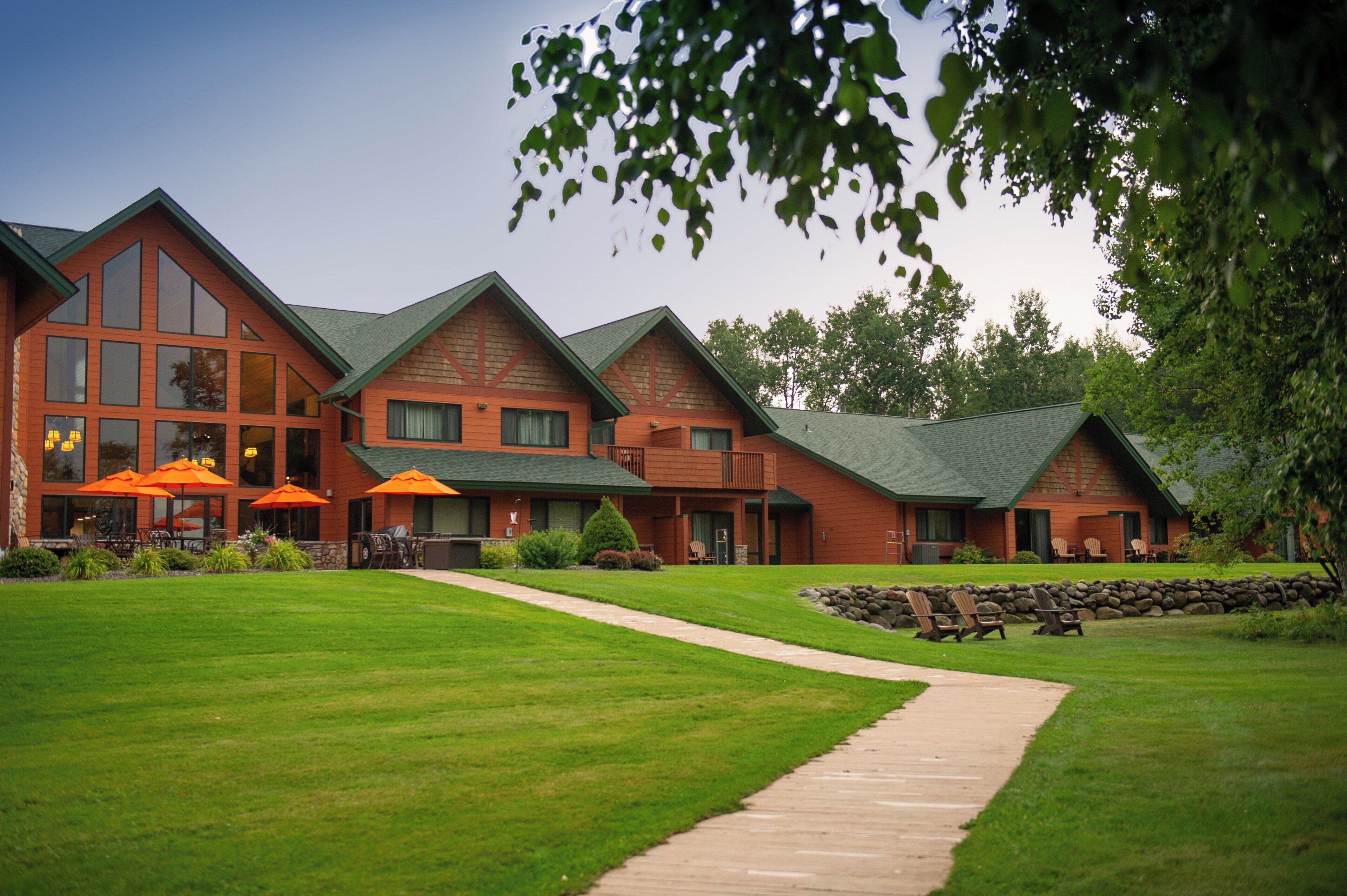 A lodge with multiple buildings, outdoor seating, and a well-maintained lawn.