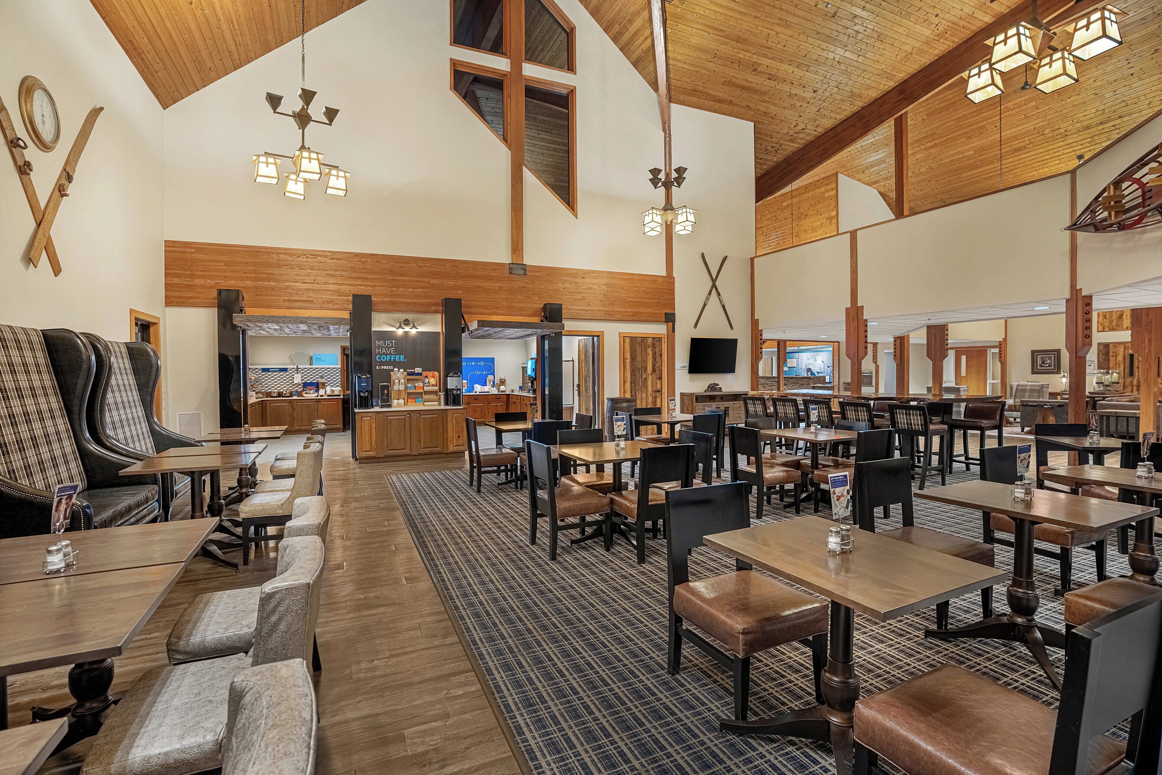 A spacious restaurant with high ceilings, wooden beams, and a variety of seating options including booths and tables.