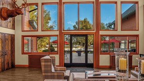 A spacious lobby with large windows, wooden furniture, and a mounted deer head. - Holiday Inn Express & Suites Hayward by IHG (Hayward)