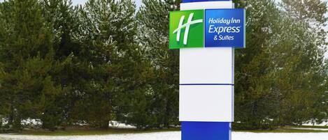 A sign for Holiday Inn Express & Suites with a clear view of the surrounding trees and snow.