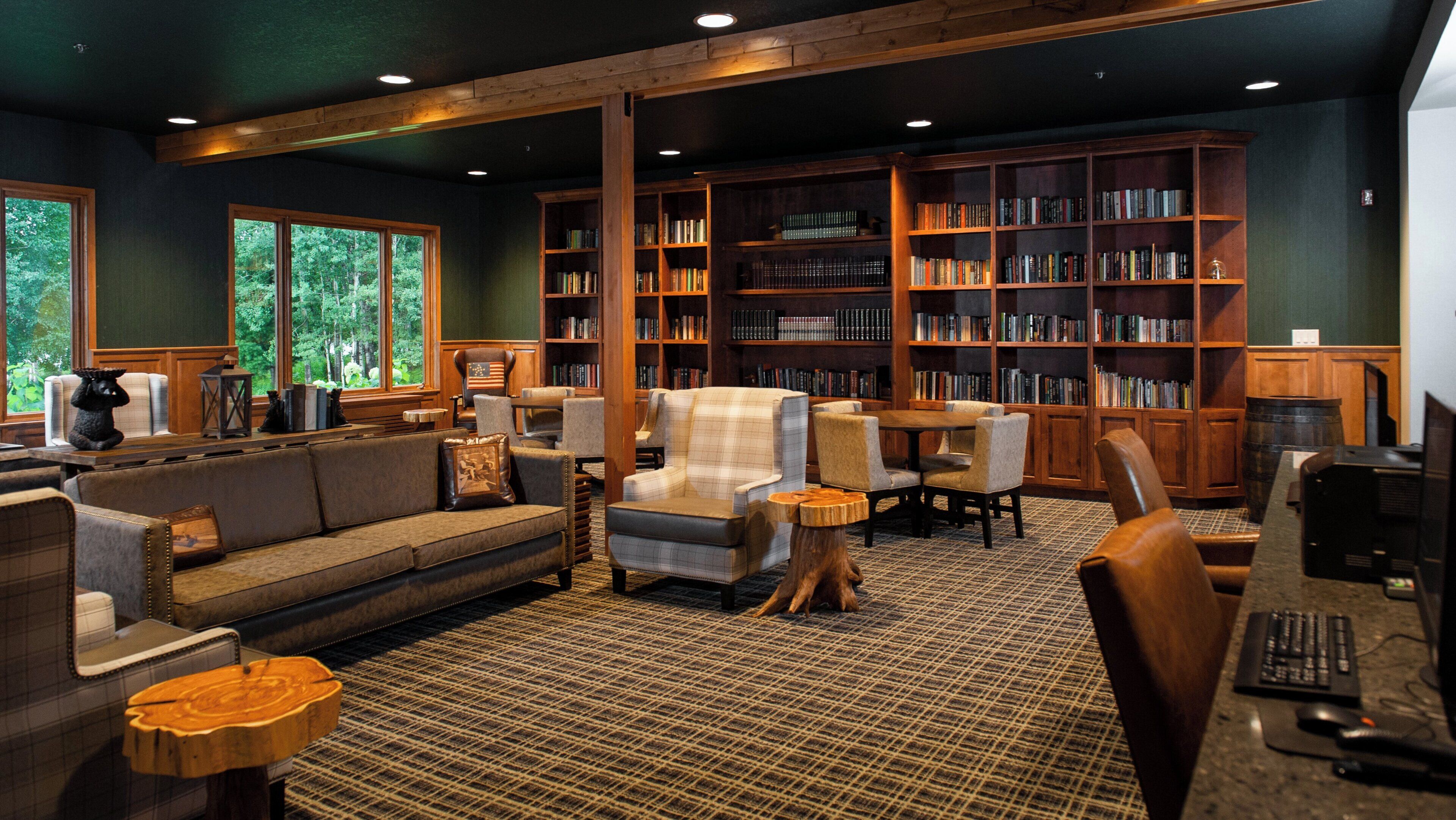 A library with bookshelves, a sofa, chairs, a table, and a computer desk.