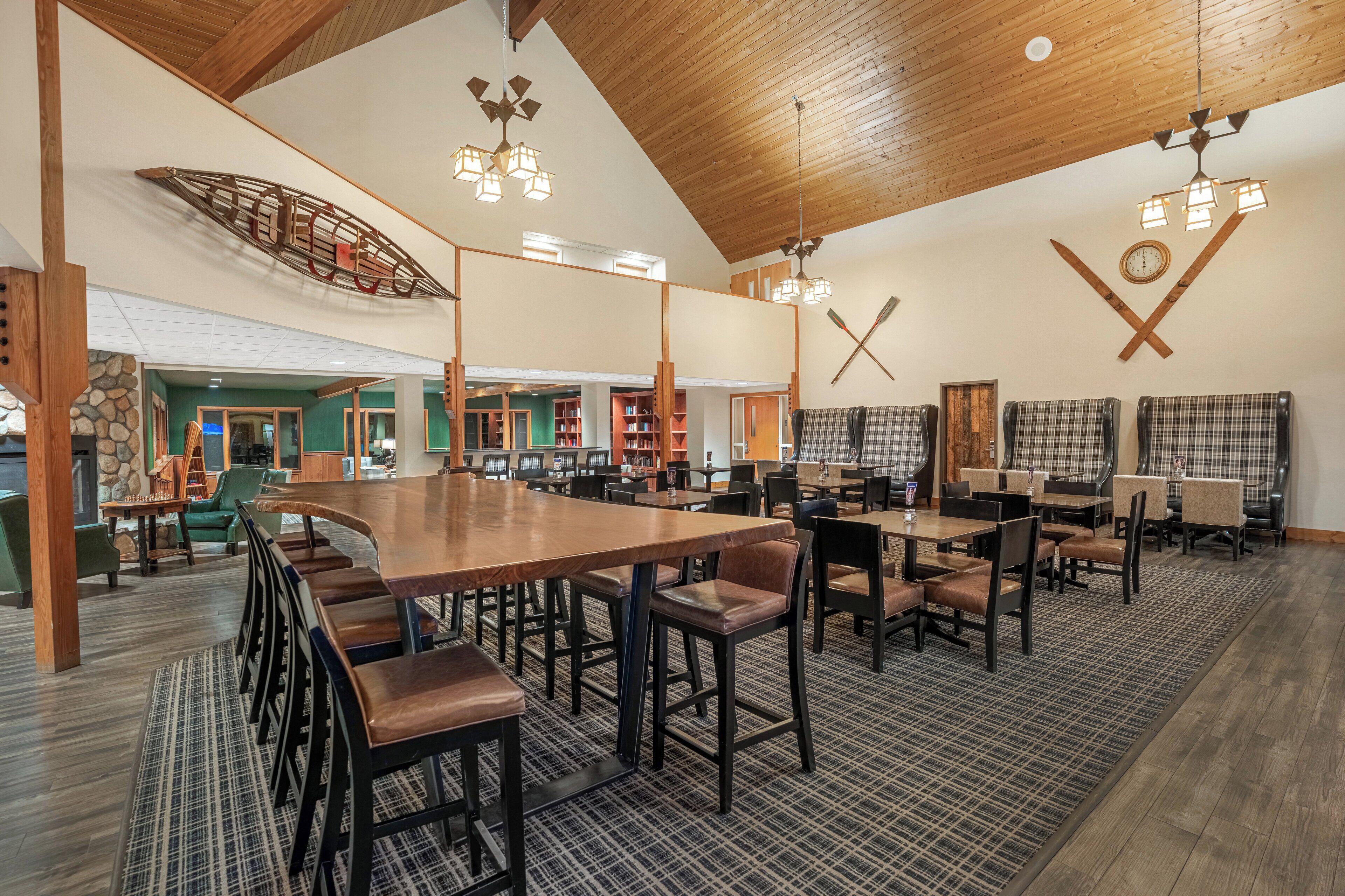 Un vaste espace dédié à la salle à manger, avec de hauts plafonds en bois, de nombreuses tables et chaises, et une grande décoration représentant un bateau en bois au plafond.