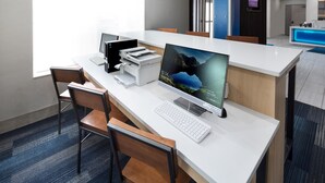 A modern office desk with a desktop computer, keyboard, and printer. There are two chairs and a large window providing natural light. - Holiday Inn Express & Suites Chicago West - St Charles by IHG (St. Charles)