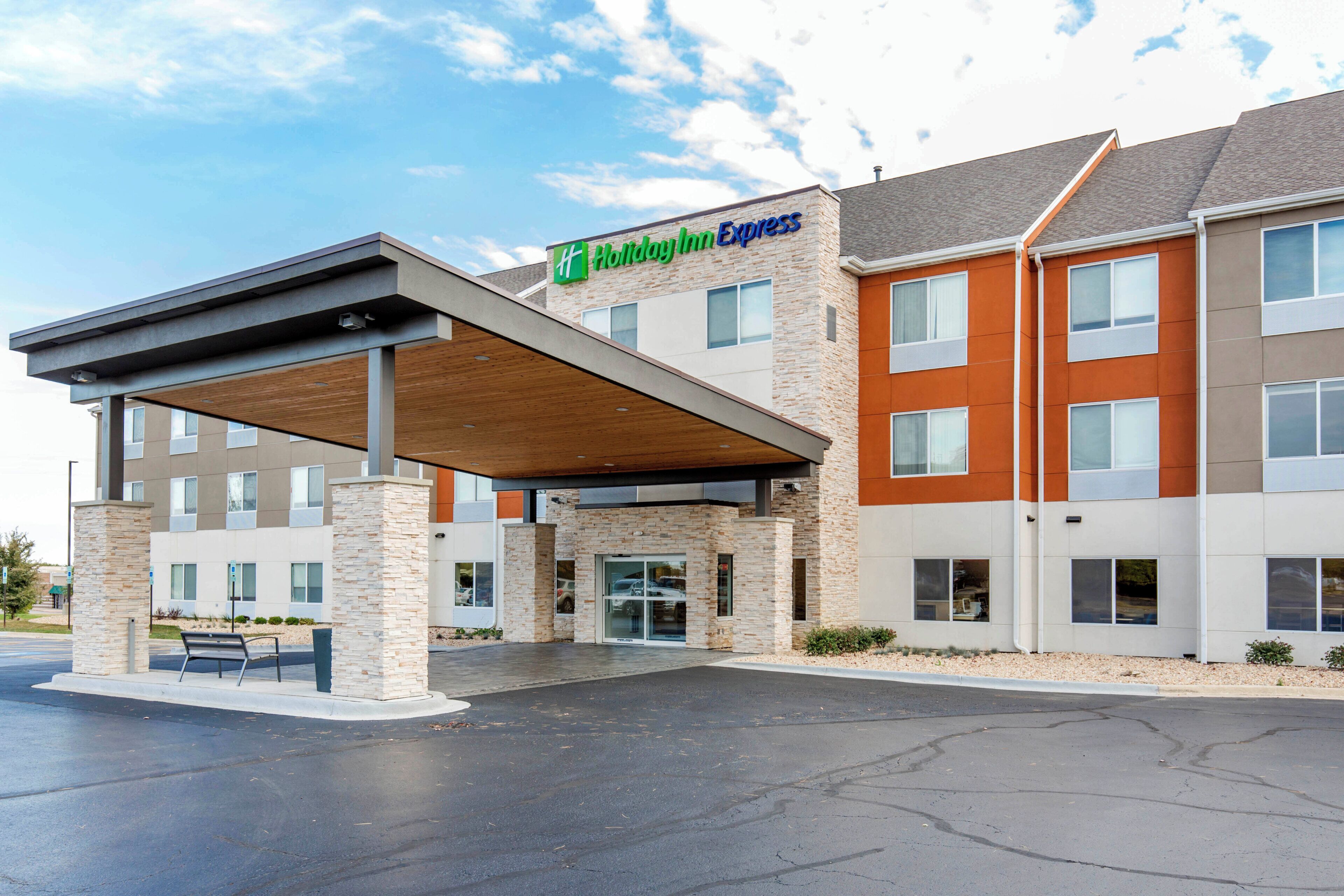 Un hotel Holiday Inn Express con ingresso coperto, colonne in pietra e parcheggio.