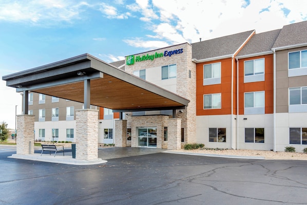 A Holiday Inn Express hotel with a covered entrance, stone pillars, and a parking lot.