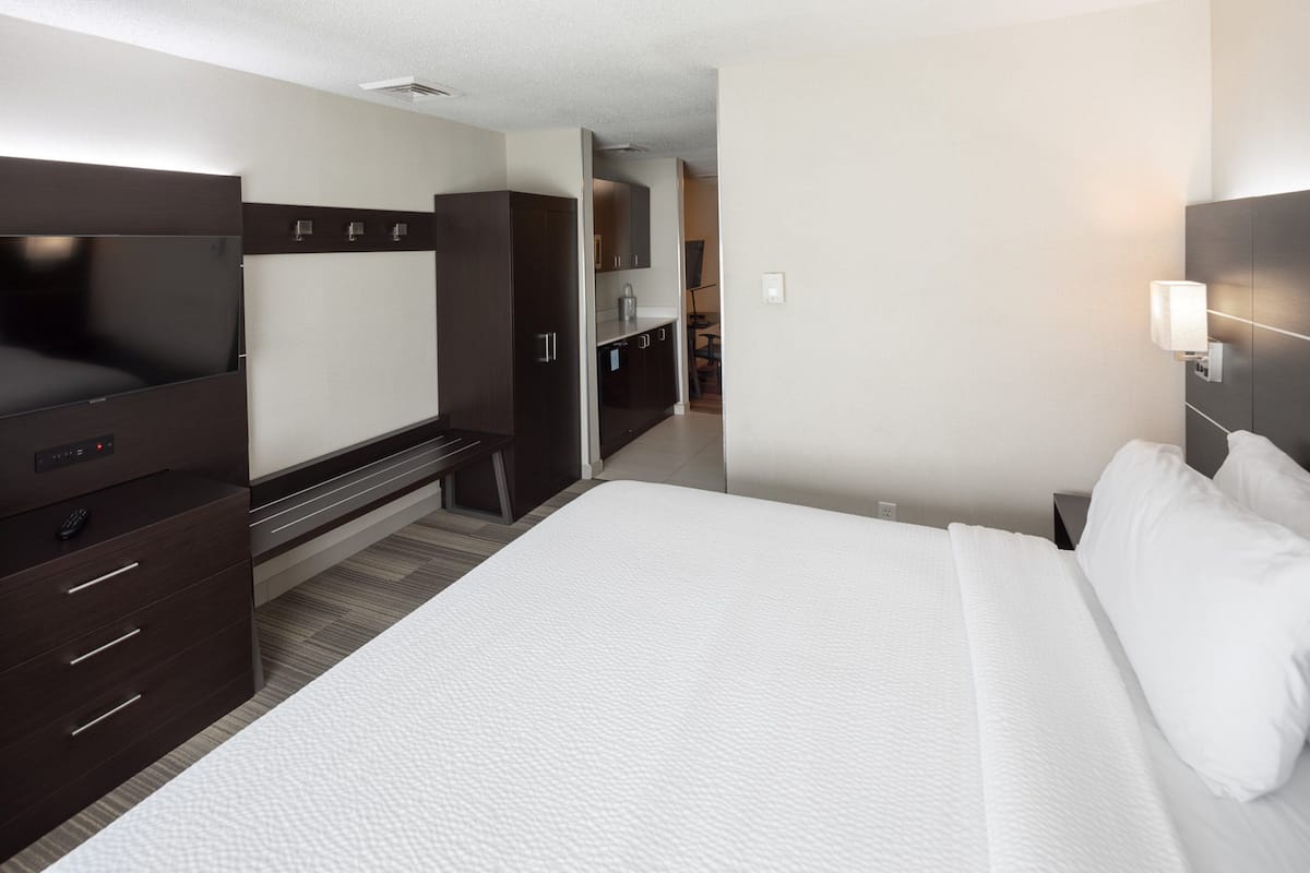 A hotel room with a bed, a TV, a desk, and a wardrobe.