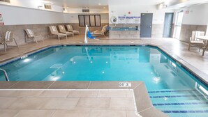 An indoor swimming pool with clear water, lounge chairs, and a reception desk. - Holiday Inn Express & Suites Chicago West - St Charles by IHG (St. Charles)