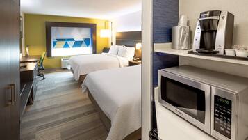 Habitación de hotel con dos camas, microondas, cafetera y escritorio con silla.