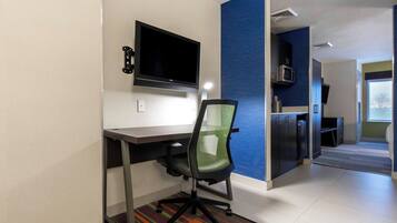 A modern office space with a flat-screen monitor, office chair, and a kitchenette area.