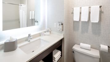 Un baño moderno con un espejo grande, un lavamanos, un inodoro y un perchero para toallas.