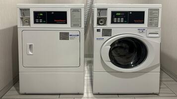 Dos lavadoras frontales blancas en un cuarto de lavado con piso de baldosas.