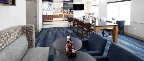 A modern hotel lobby with a seating area, a bar, and a dining space.