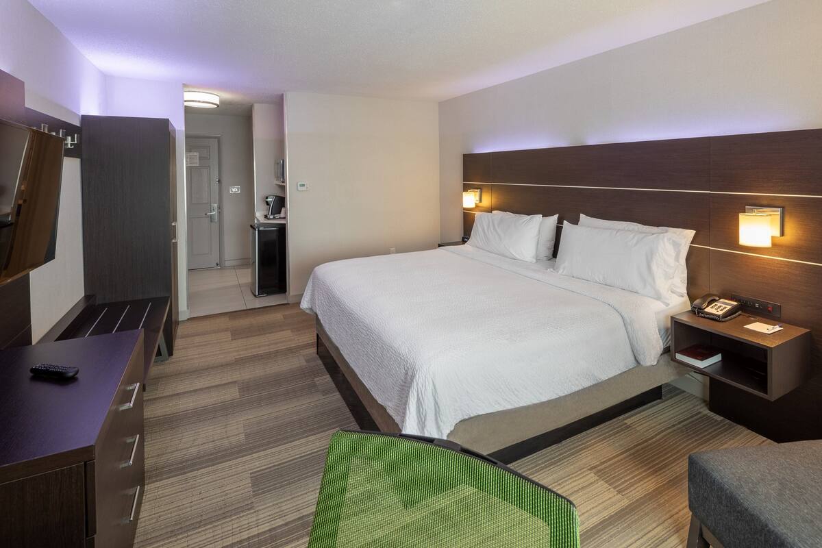 A hotel room with a large bed, bedside tables, a desk, and a chair.