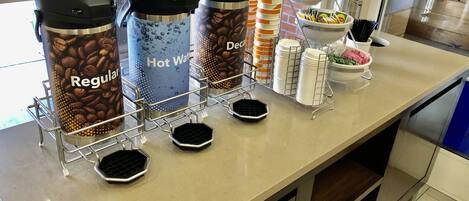 A coffee station with three dispensers labeled 'Regular', 'Hot Water', and 'Decaf'.