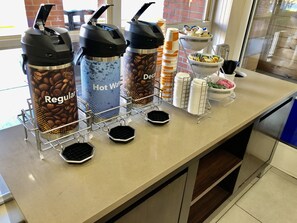 Una estación de café con tres dispensadores etiquetados como 'Regular', 'Agua Caliente' y 'Descafeinado'.