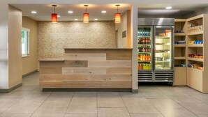 Un espace d’accueil comprenant un comptoir de réception en bois, un mur en pierre et un réfrigérateur rempli de boissons.