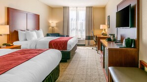 Une chambre d’hôtel avec deux lits, un bureau, une télévision et une fenêtre avec des rideaux.