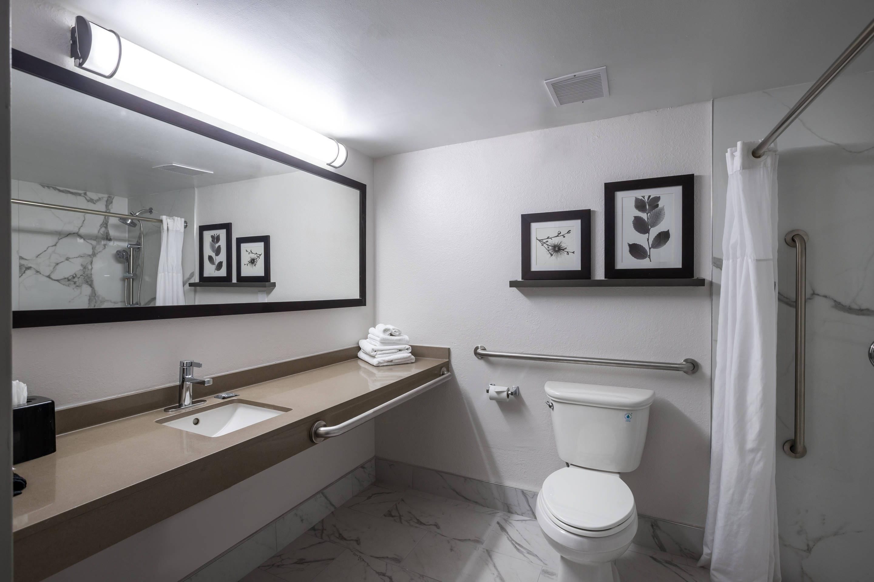 Een moderne badkamer met een marmeren vloer, een wastafelmeubel met dubbele wastafel, een toilet en een douchegedeelte.