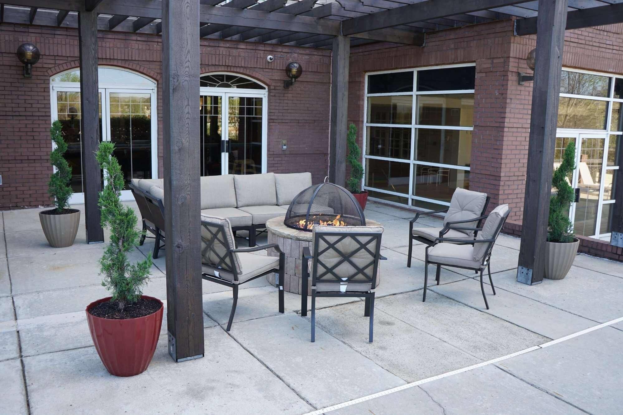An outdoor patio with a fire pit, seating, and potted plants.