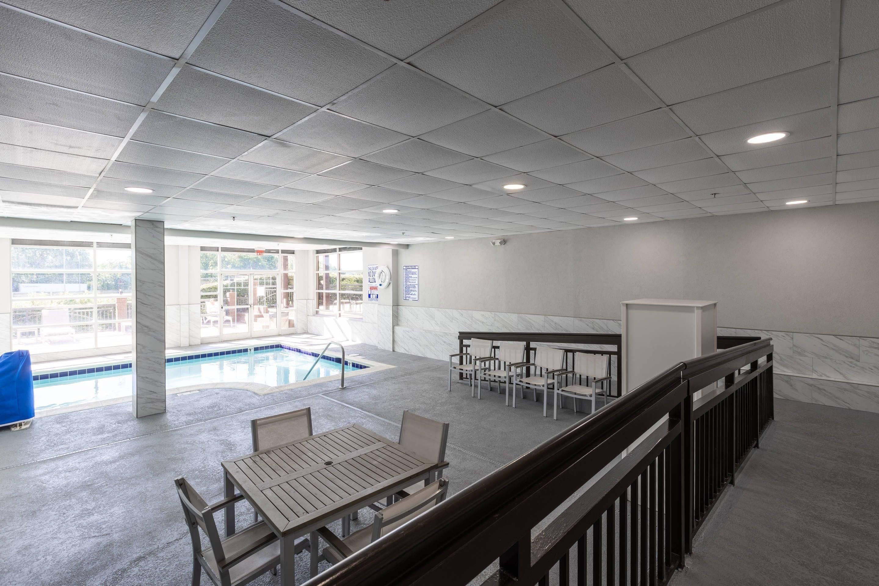 A spacious indoor area with a pool, seating, and a view of the outside.