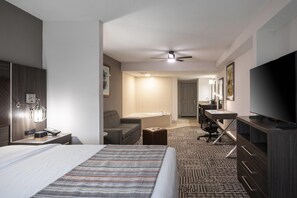 A hotel room with a bed, a desk, a chair, a television, and a ceiling fan. - Country Inn & Suites by Radisson, Lake Norman Huntersville, NC (Huntersville)