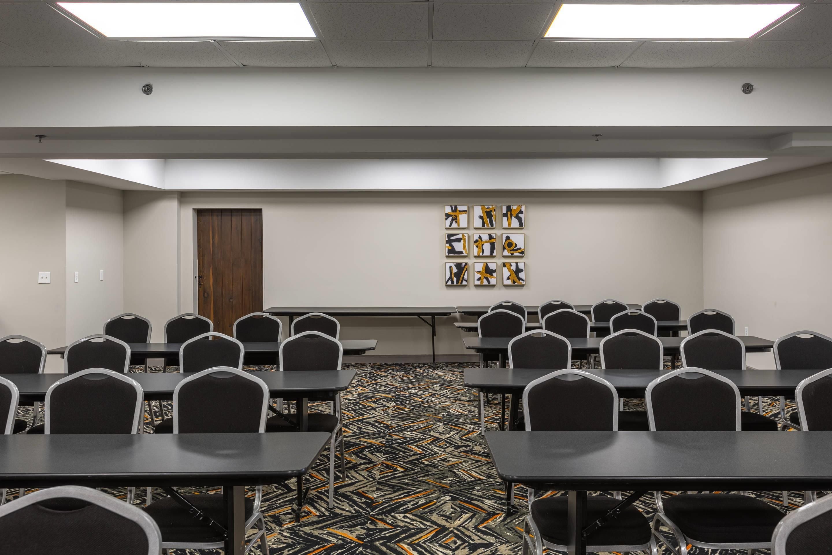 Uma sala de conferências com uma mesa comprida, várias cadeiras e um tapete estampado.