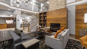 A spacious living area with a fireplace, modern furniture, and a staircase leading to an upper level.