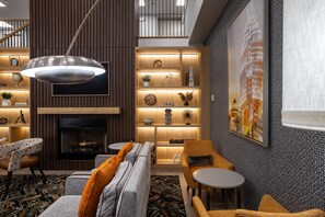 A modern interior with a fireplace, wooden shelving, and a large cityscape painting. - Country Inn & Suites by Radisson, Lake Norman Huntersville, NC (Huntersville)