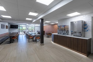 A modern restaurant with a long counter, seating area, and a large window.