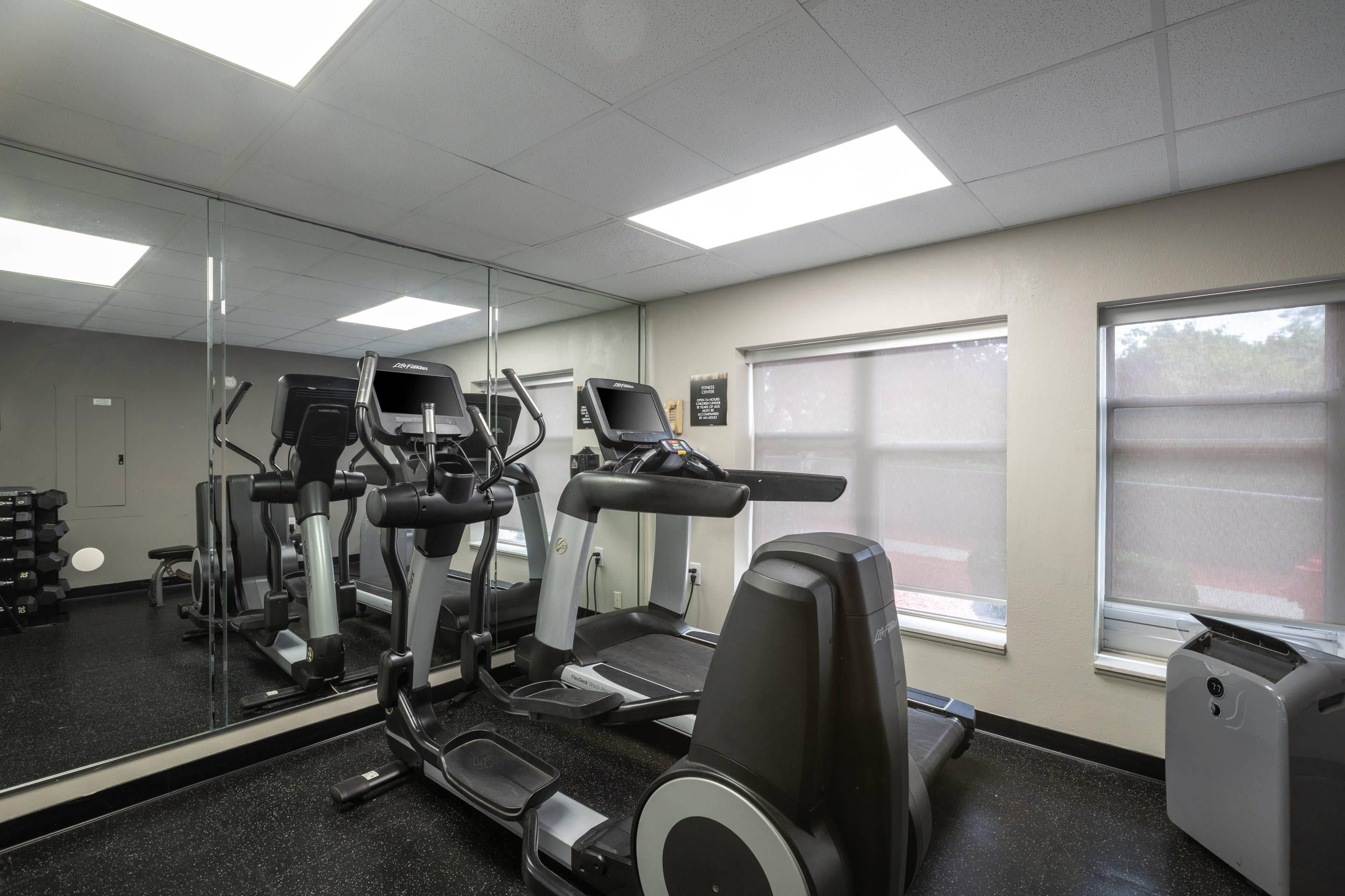 A gym with exercise equipment, a large mirror, and a window.