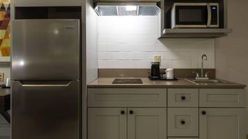 A kitchen with a stainless steel refrigerator, a microwave, a coffee maker, and a sink.