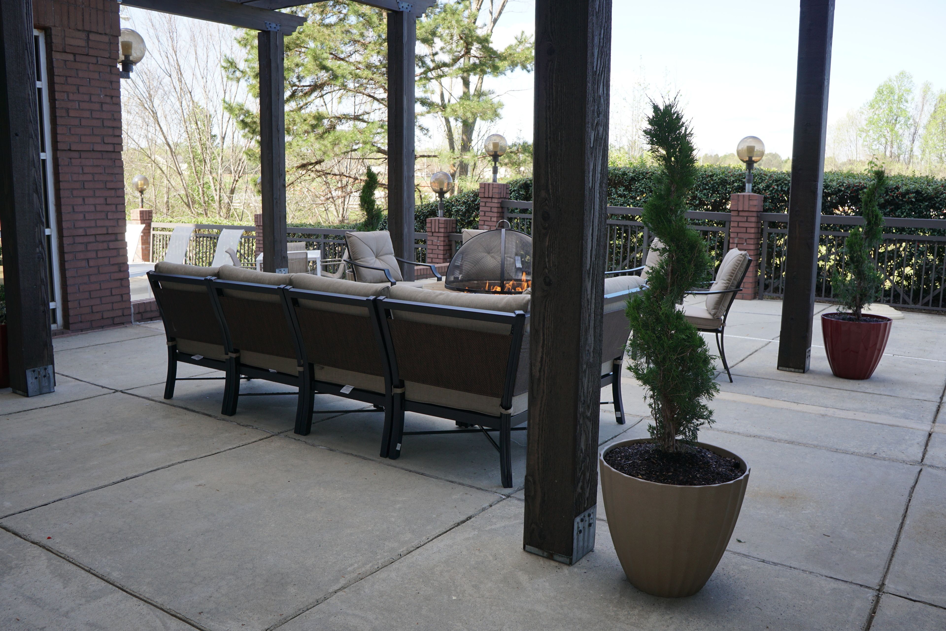 Une terrasse extérieure dotée d’un foyer, d’un espace salon et de plantes en pot.