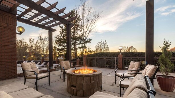 A patio area with a fire pit, outdoor seating, and a pergola.