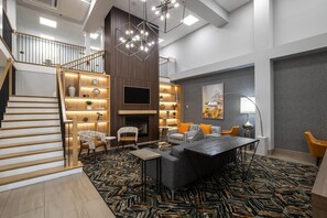 A modern interior with a staircase, a fireplace, a dining area, and a living room with a patterned carpet. - Country Inn & Suites by Radisson, Lake Norman Huntersville, NC (Huntersville)