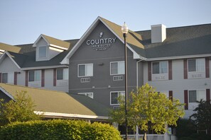 A Country Inn & Suites building with a grey facade, white trim, and red shutters.