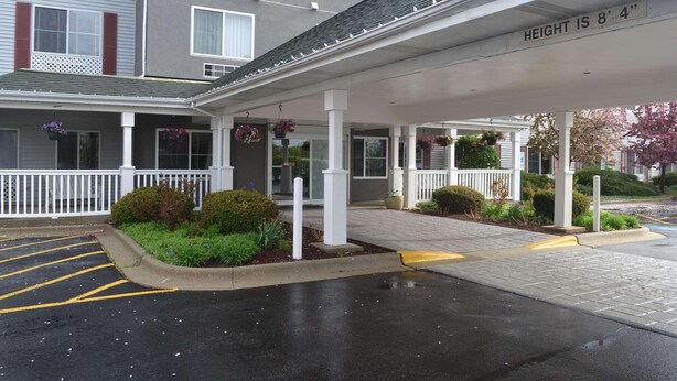 A covered outdoor area with a white railing, potted plants, and a sign indicating the height of the building. - Country Inn & Suites by Radisson, Gurnee, IL (Gurnee)