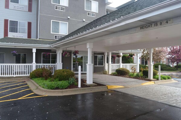 Enter a charming hotel with a covered walkway supported by pillars and adorned with hanging flower baskets.