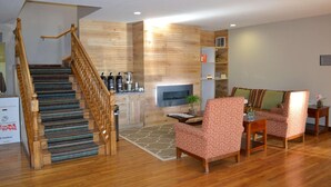 A spacious living area with a wooden staircase, a fireplace, and a seating area with patterned chairs. - Country Inn & Suites by Radisson, Gurnee, IL (Gurnee)