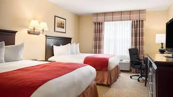 A hotel room with two beds, a desk with a chair, a television, and a window with curtains.