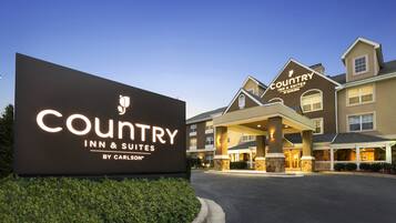 Edificio di un Country Inn & Suites by Carlson con un grande cartello illuminato, un ingresso coperto e una facciata curata.