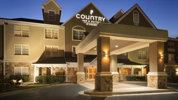 A Country Inn & Suites building with a covered entrance, stone pillars, and a well-lit facade.