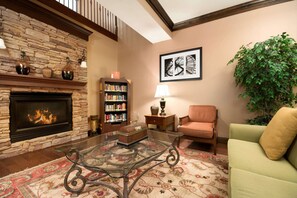 A cozy living room with a stone fireplace, a bookshelf, a coffee table, and a comfortable seating area.