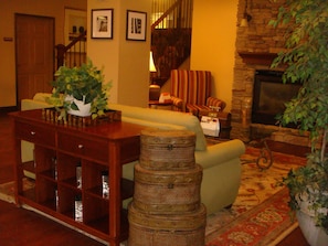 A cozy living room with a fireplace, a green sofa, a wooden coffee table, and a striped armchair. - Country Inn & Suites by Radisson, Norcross, GA (Norcross)