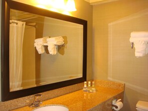 Un baño con lavamanos, espejo y toallero.