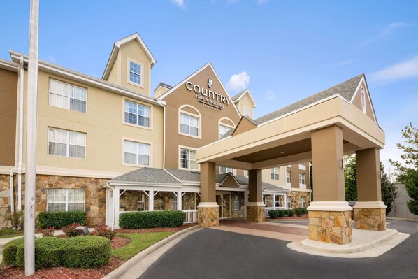 A Country Inn & Suites building with a stone facade, multiple windows, and a covered entrance area. - Country Inn & Suites by Radisson, Norcross, GA (Norcross)