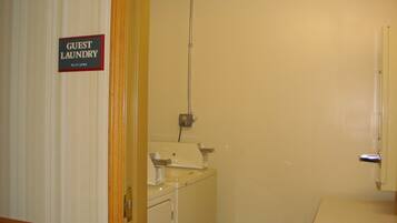 A guest laundry area with a sign, a washing machine, and a sink.